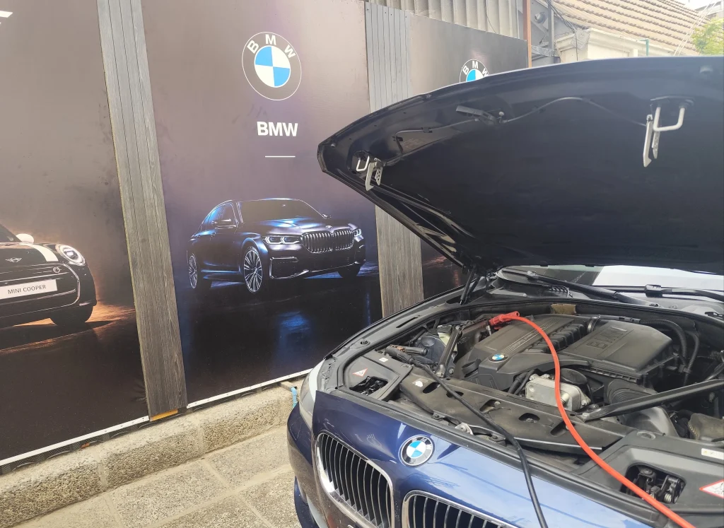 BMW Serie 5 con el capó abierto durante el cambio y registro de batería en NELLA BMW, Ñuñoa